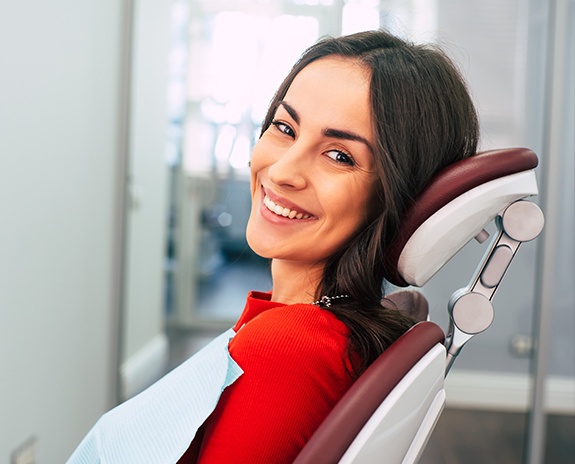 Dental team member smiling behind dental office reception desk