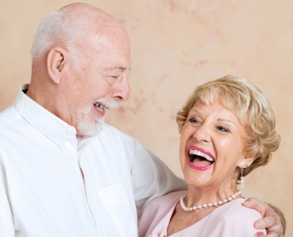 Man and woman smiling together after full mouth reconstruction