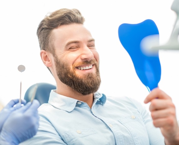 Man looking in the mirror after smile makeover