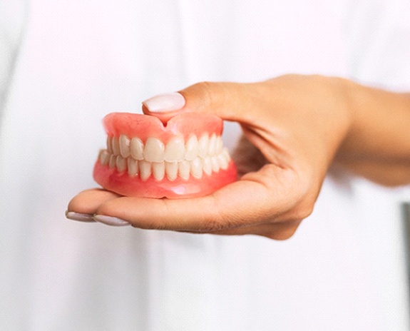 Dentist holding full dentures in Florence