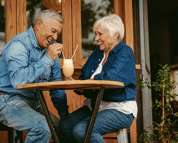 Senior couple with dentures in Florence sharing a milkshake