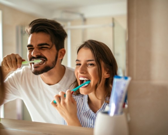 Man and woman brushing teeth to prevent dental emergencies