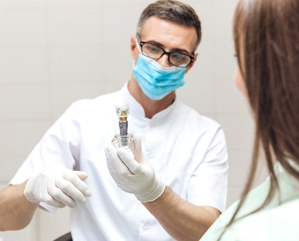 dentist showing patient a dental implant
