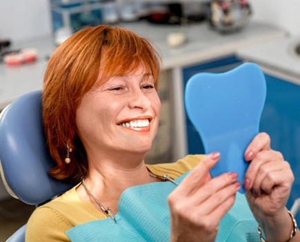 Woman with dental implants smiling at dentist office