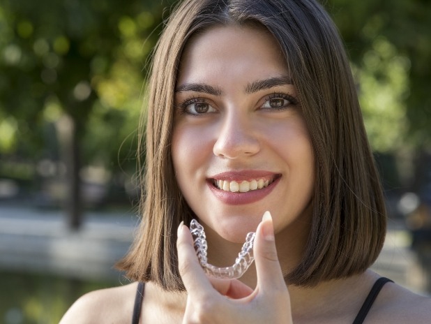 Smiling woman placing an Invisalign orthodontics tray