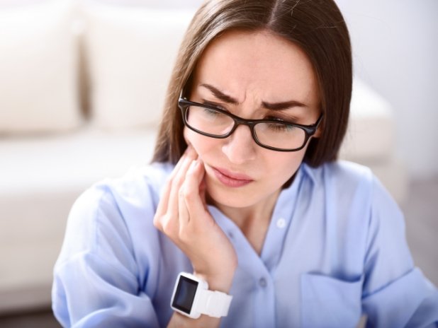 Woman in need of T M J therapy holding jaw in pain