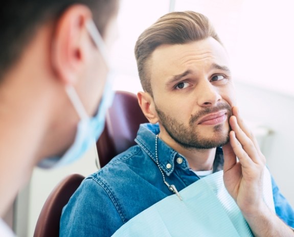 Man in need of T M J therapy holding jaw