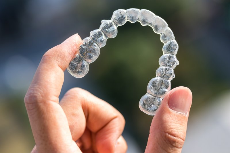 person holding up Invisalign aligner